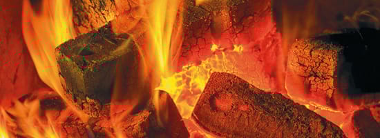 Glühende Holzbriketts lodern mit intensiven Flammen in einer Feuerglut. Die brennenden Briketts erzeugen eine warme, angenehme Atmosphäre, die ideal für gemütliche Abende ist.